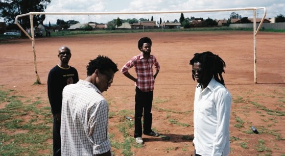 four black men are playing soccer in a field
