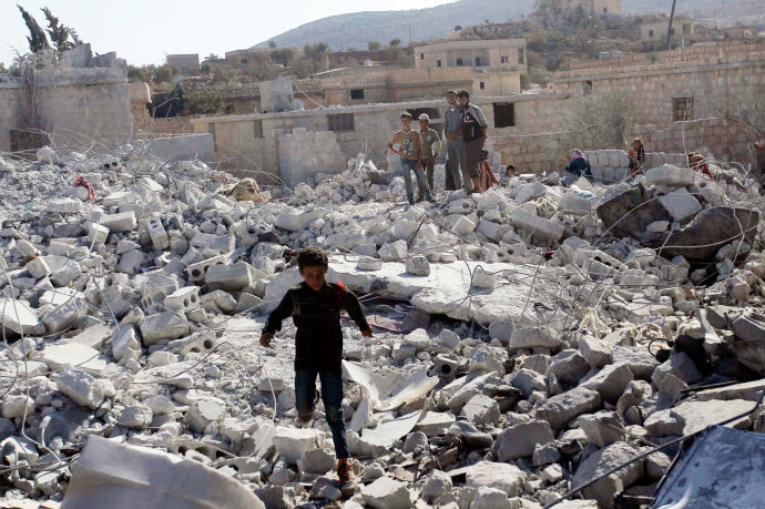 young children in rubble, surrounded by soldiers