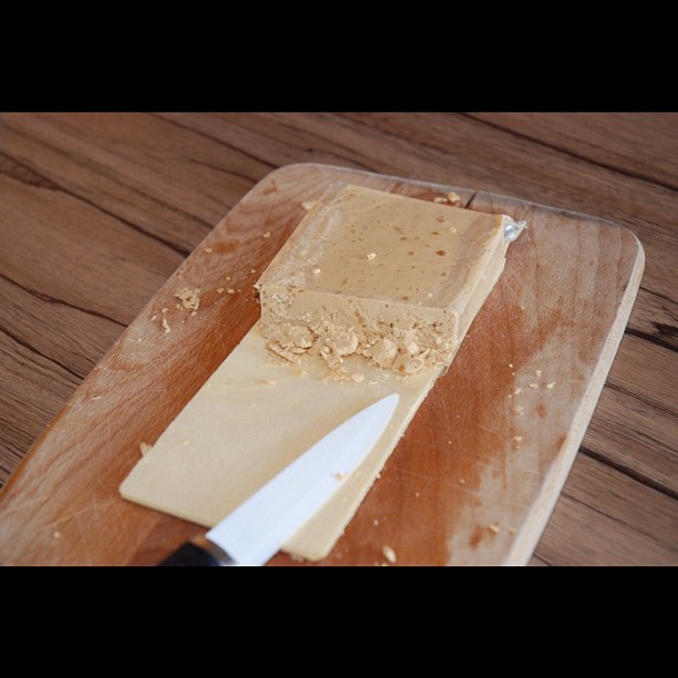 a block of cheese on a  board with a knife