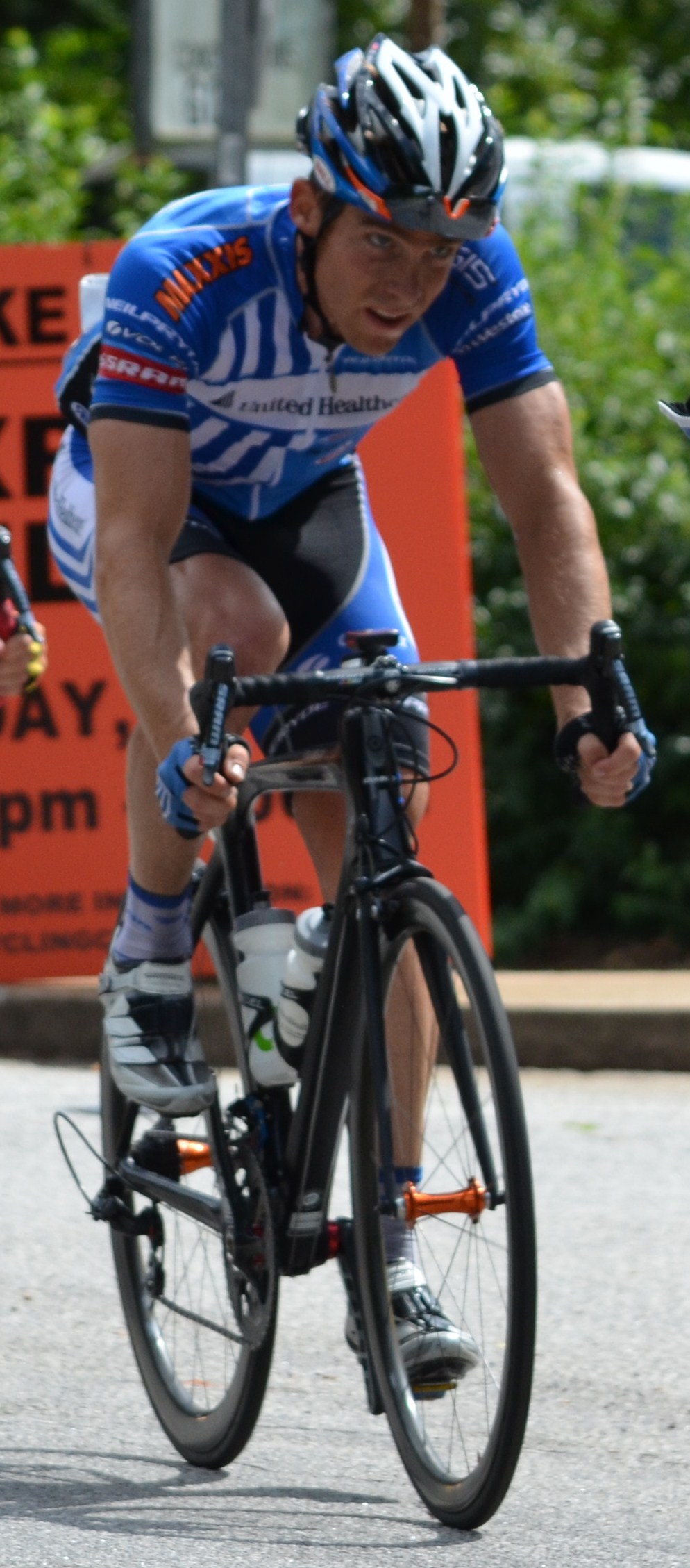 a male cyclist is looking over his shoulder as he rides