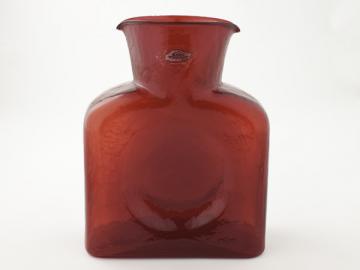 a red glass vase sits on top of a table