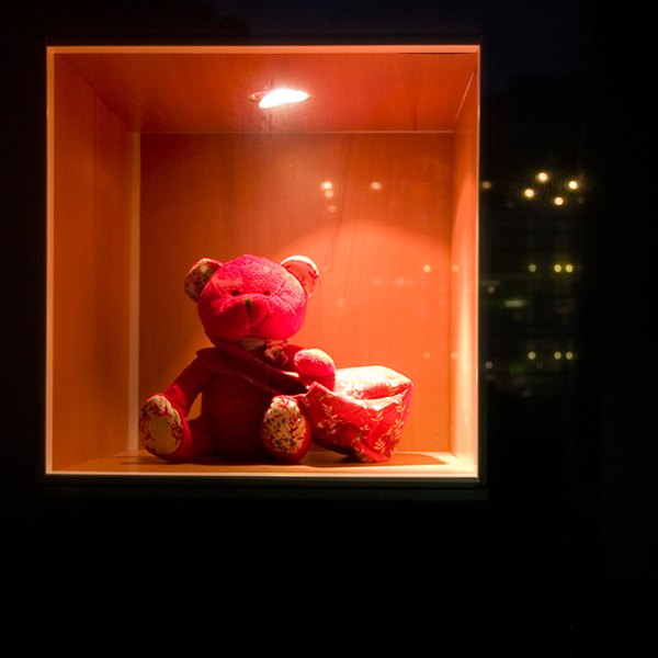 a teddy bear is in a glass box with lights