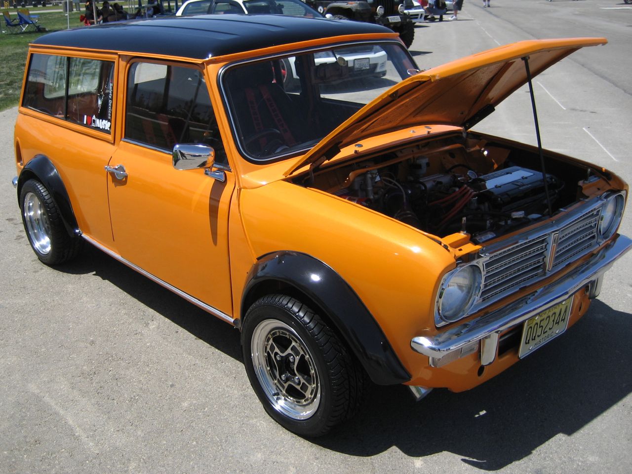 an orange car with its hood open sitting in the street