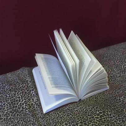 an open book with a long curved page on top of a leopard print tablecloth