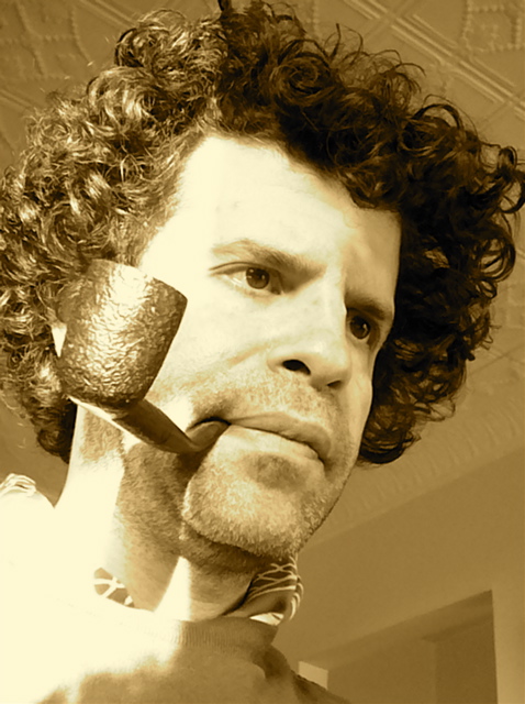a man with curly hair wearing a neck tie and smoking a pipe