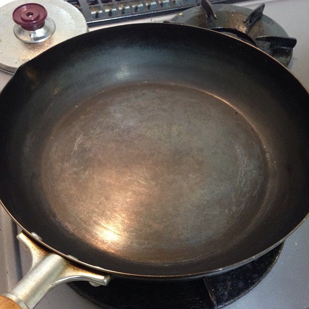 an iron pan sits on a stove top next to a plate with a spatula
