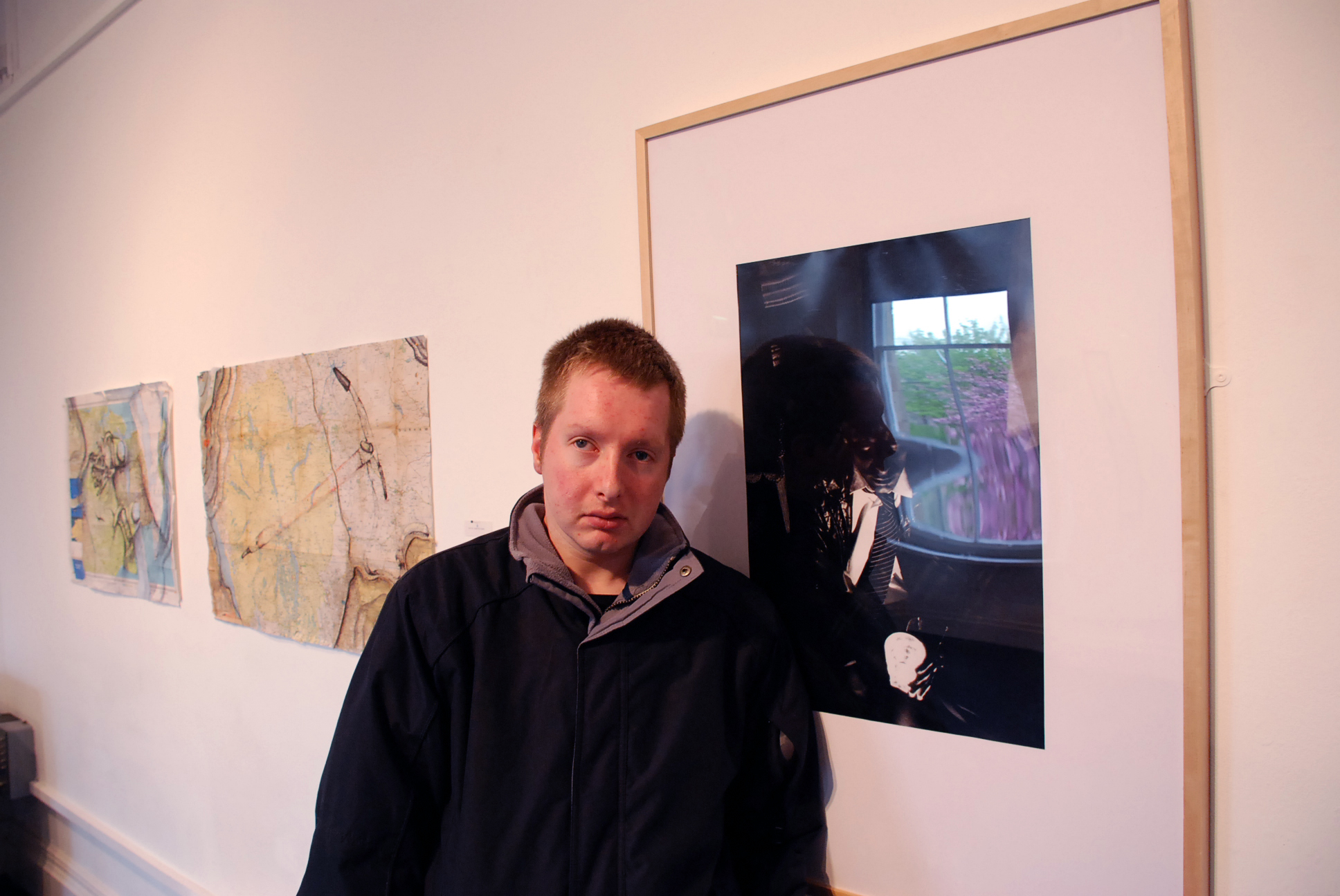 the man is standing near some paintings on the wall