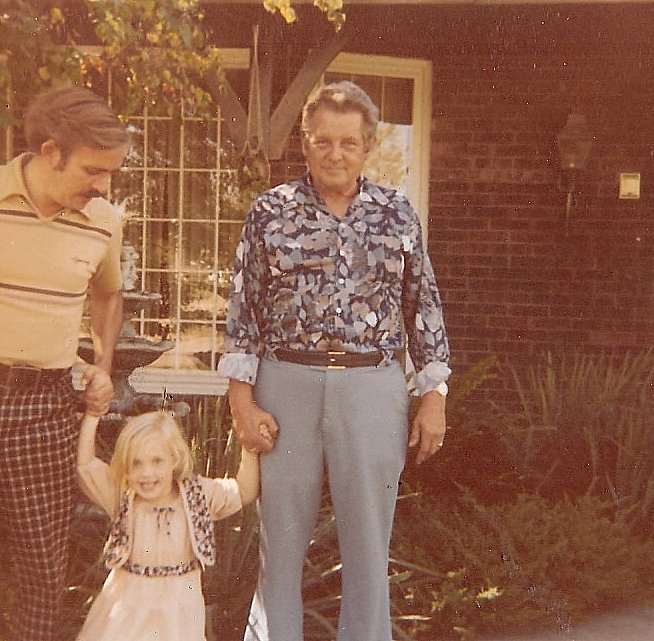 two adults and a child standing together holding hands