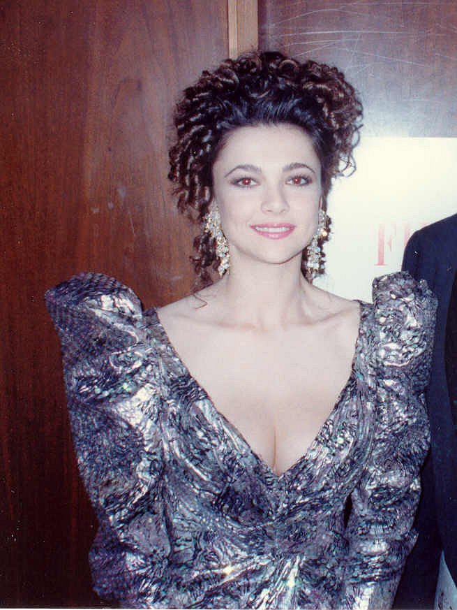 a woman with dark hair in a shiny dress stands next to a man in a tuxedo