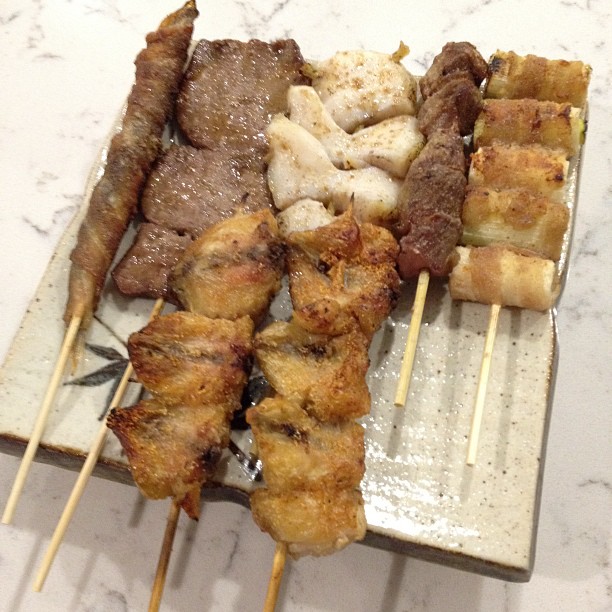 skewered meats and sauce on metal plate on marble surface