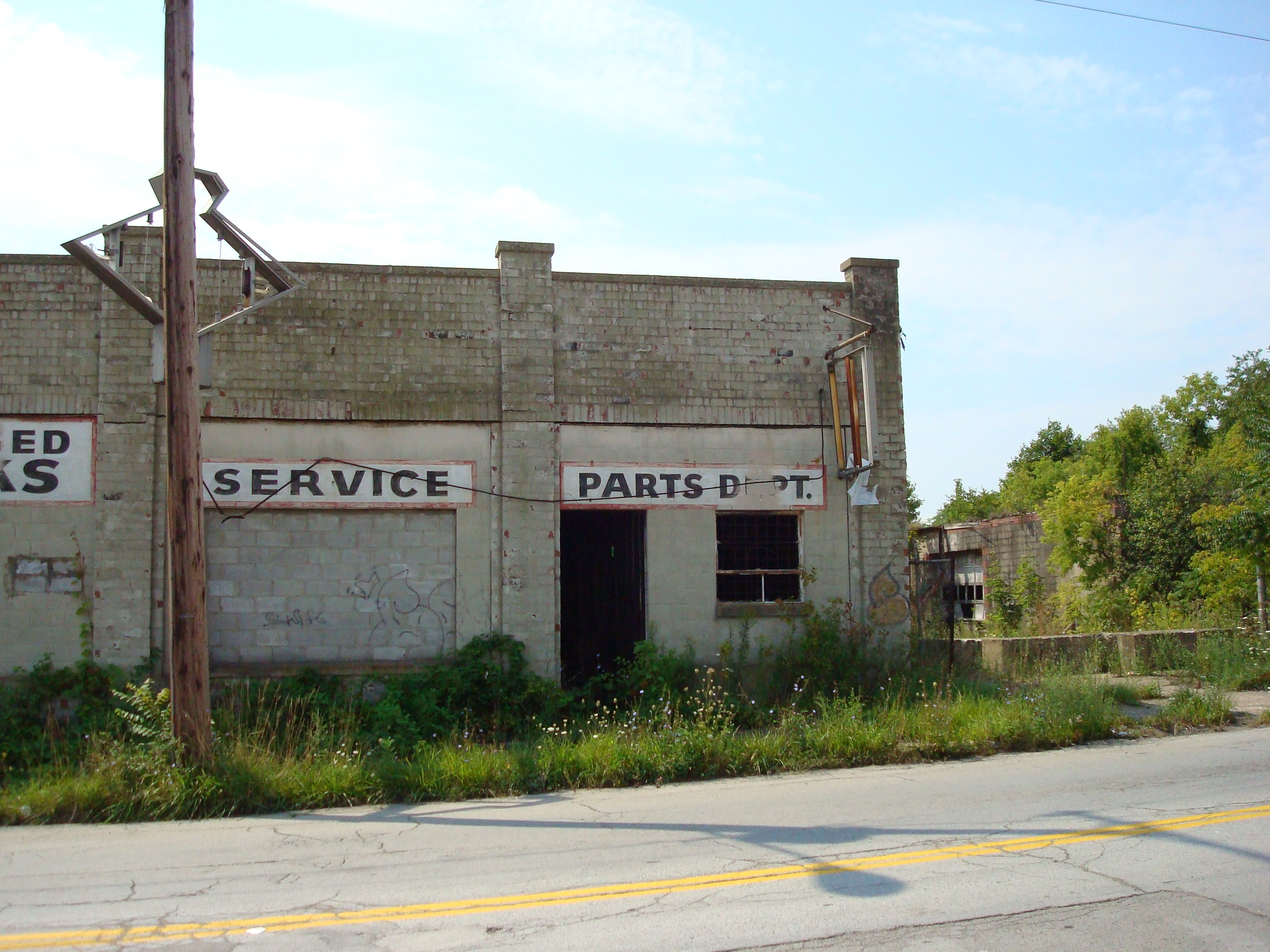 an old brick building with some plants growing out the front