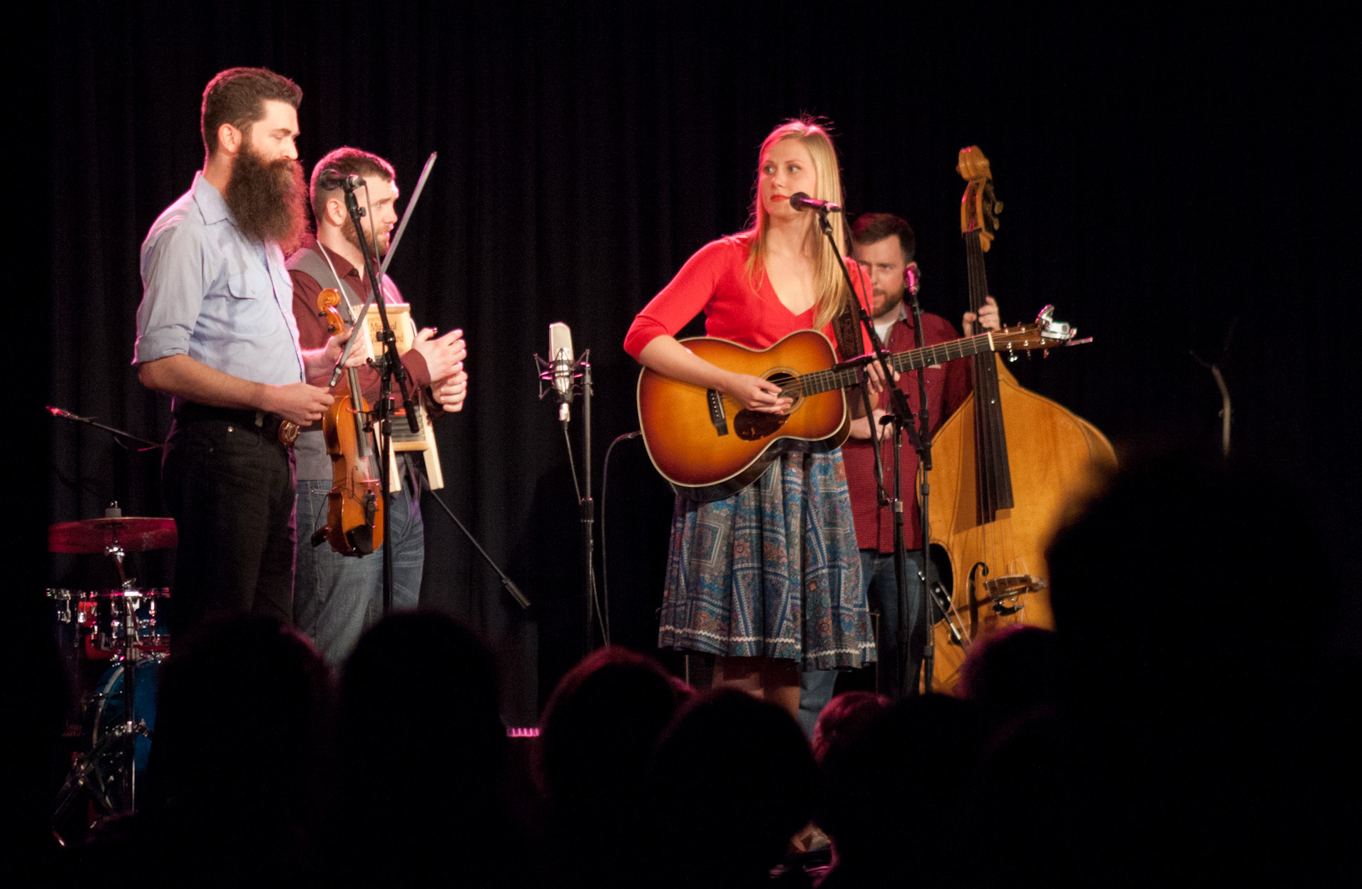 the three performers stand behind each other while playing