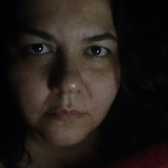 a woman with dark eyes stares to her left