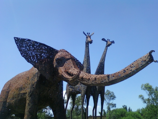 an elephant sculpture sitting in front of the trees