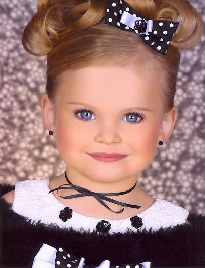 a small girl with a black polka dot bow tie