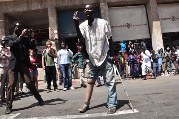 man holding a stick standing in the middle of street