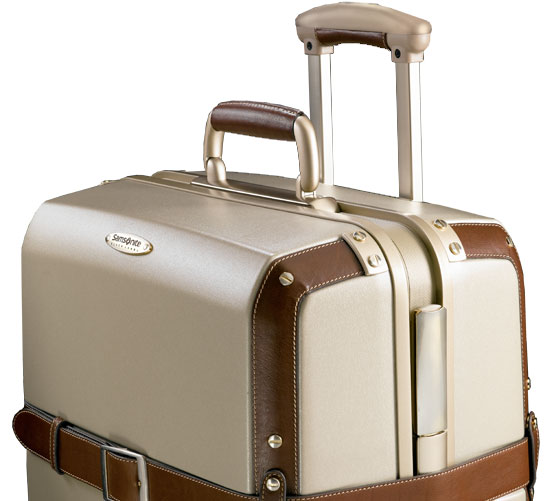 the tan piece of luggage is on wheels with brown handles