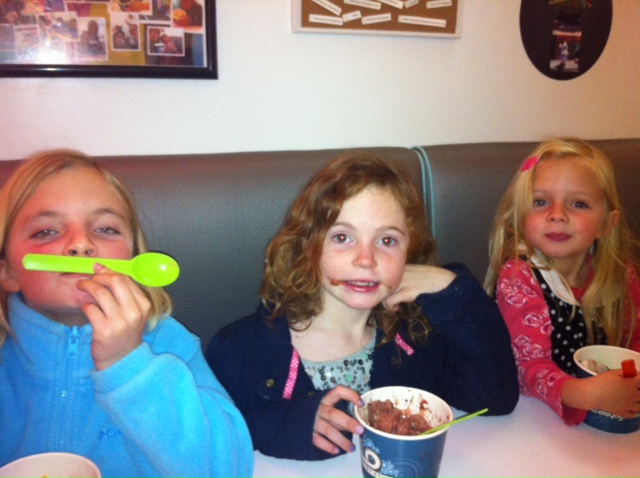 three children eating cereal at a booth in a restaurant