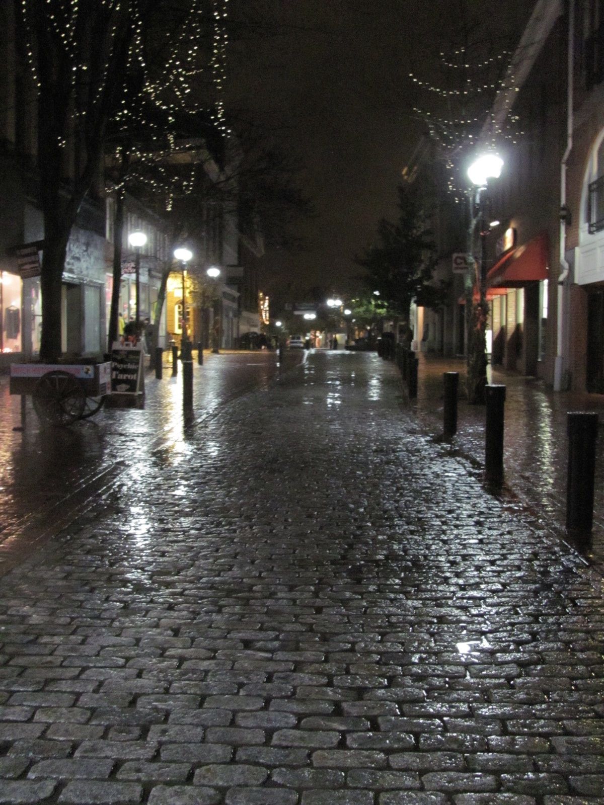 night scene of wet brick city street, light shines in