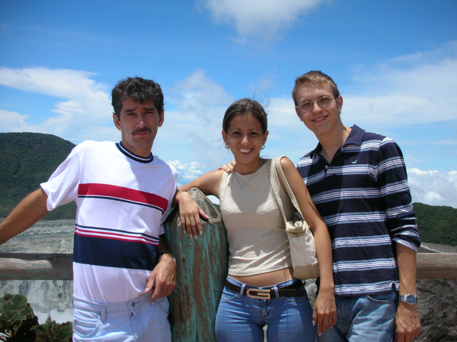 three people standing next to each other near a cliff