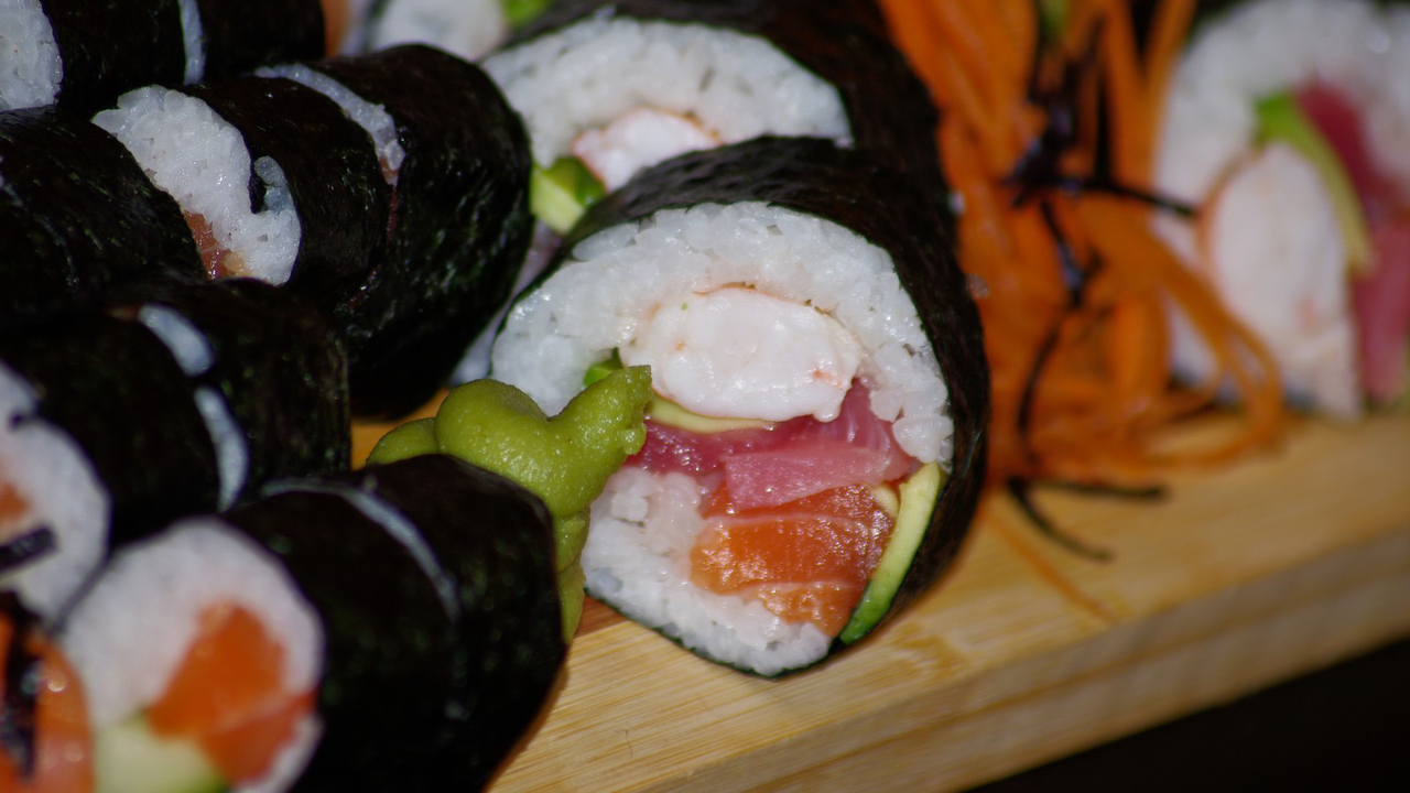 a group of sushi rolls sit on a wooden surface