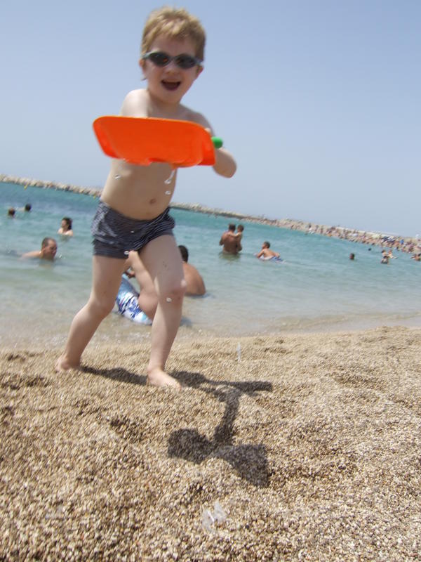 a little boy holding a frisbee on a beach