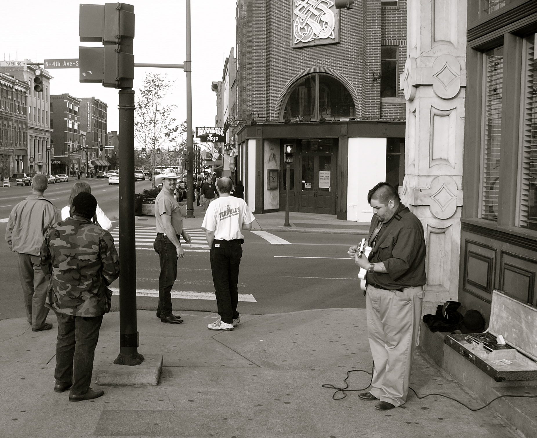 a group of people wait at an intersection to cross the street