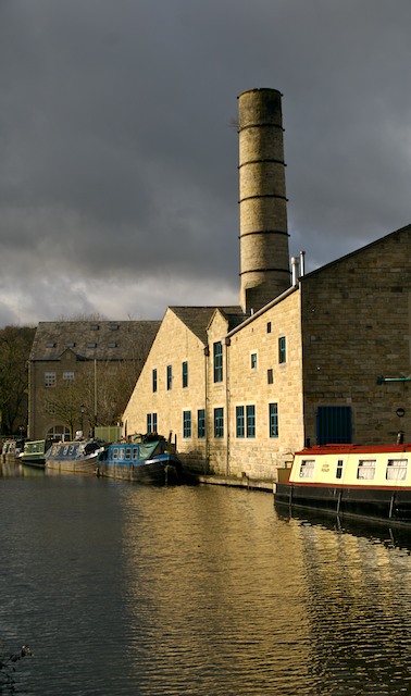 a barge sitting by some docks and smoke stack