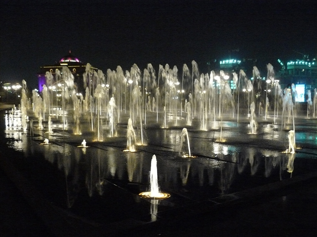 fountains light up in the night as the city lights