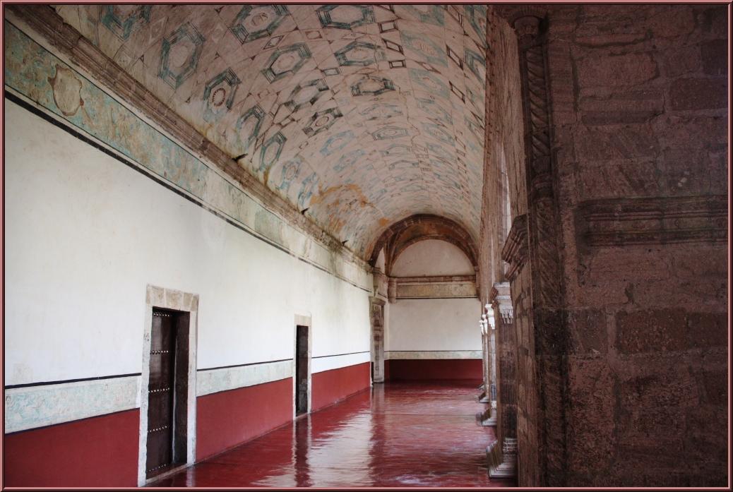 a long hallway in an old building that has red paint on the floor