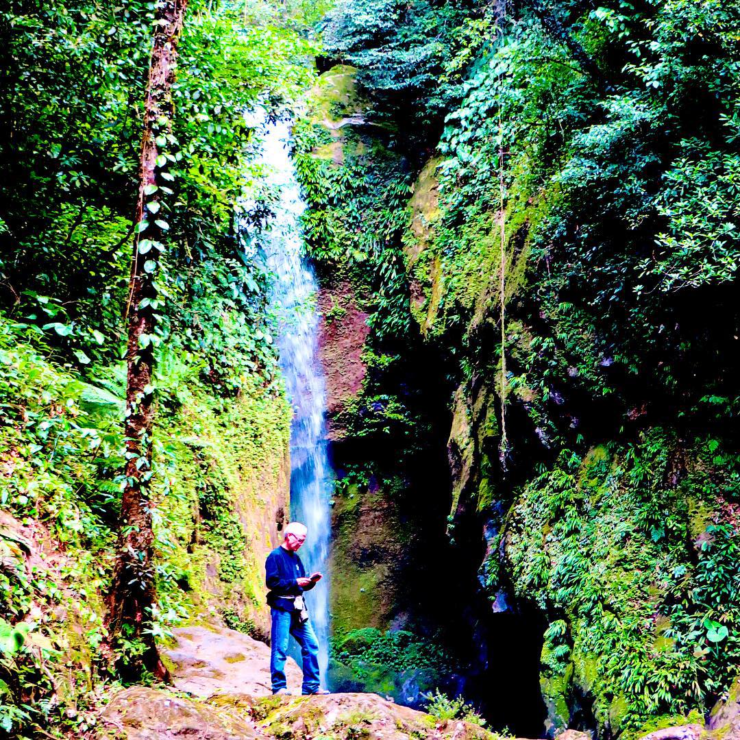 there is a man that is standing near a waterfall