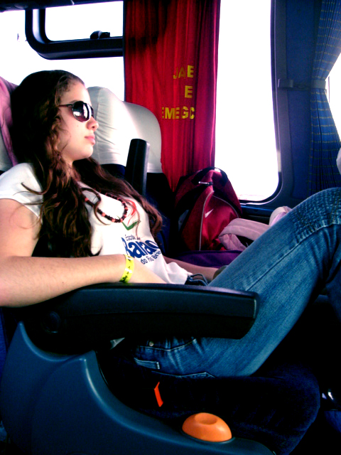 a woman wearing sunglasses on a bus with her arm up