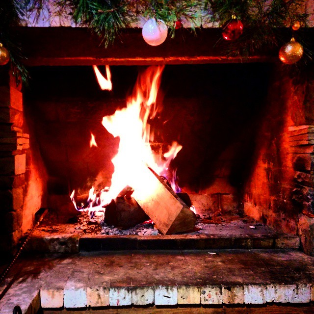 a fire is burning in the fireplace and some ornaments are on top
