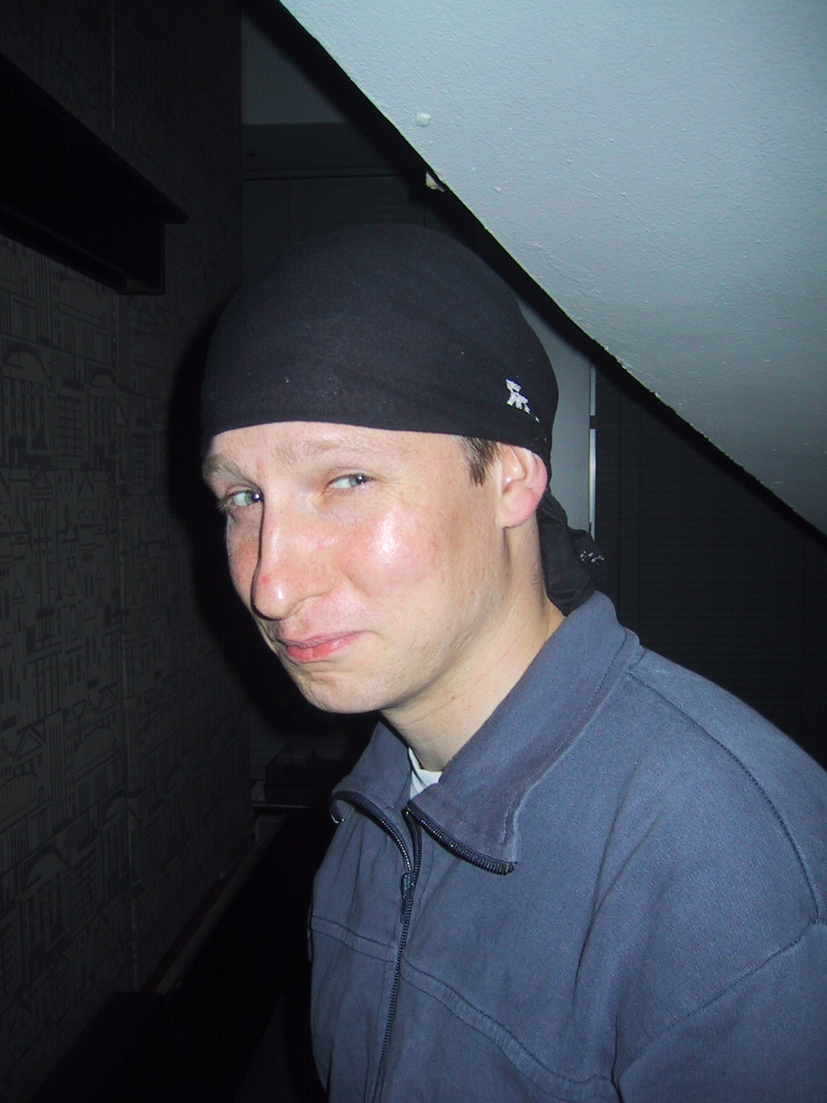 a young man in a black hat stands near a wall