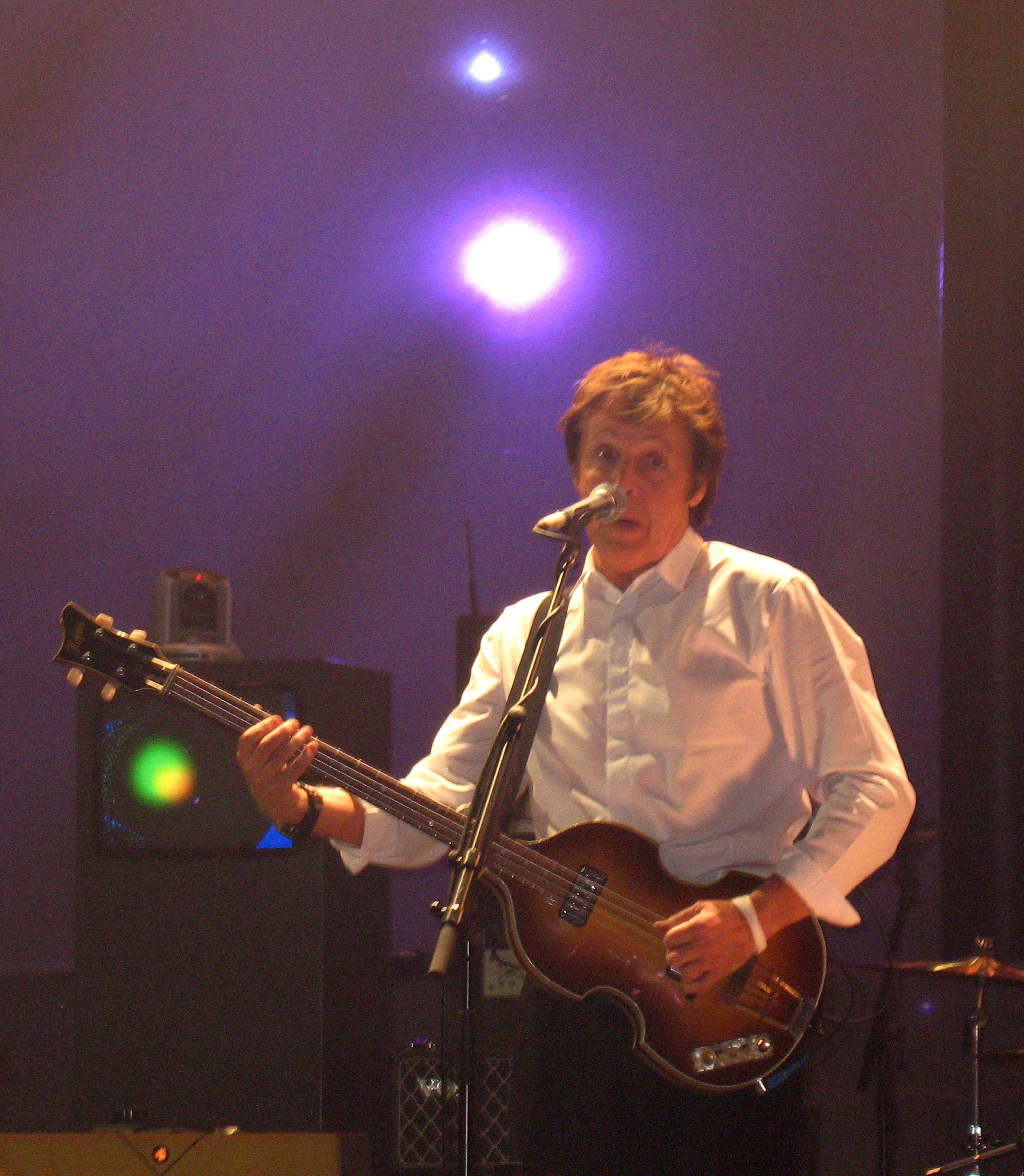 a man in white shirt playing guitar on stage