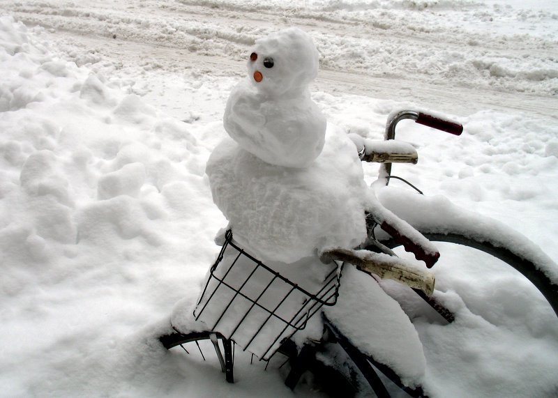 snow covered bicycle with a snowman in the basket