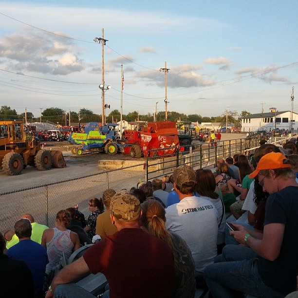 people sit in a stadium watching a tractor