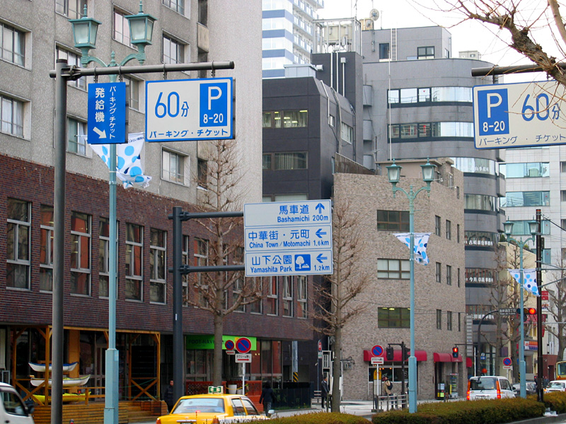 an asian street intersection with parking and walking signs in a city