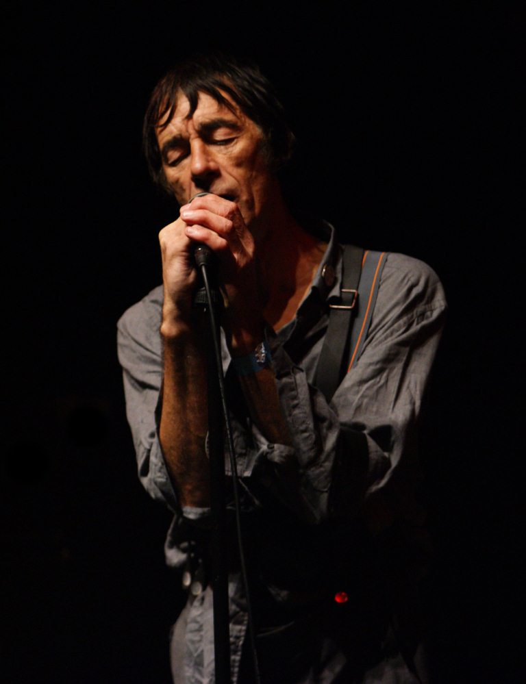 a male singer holding his microphone and looking at the crowd