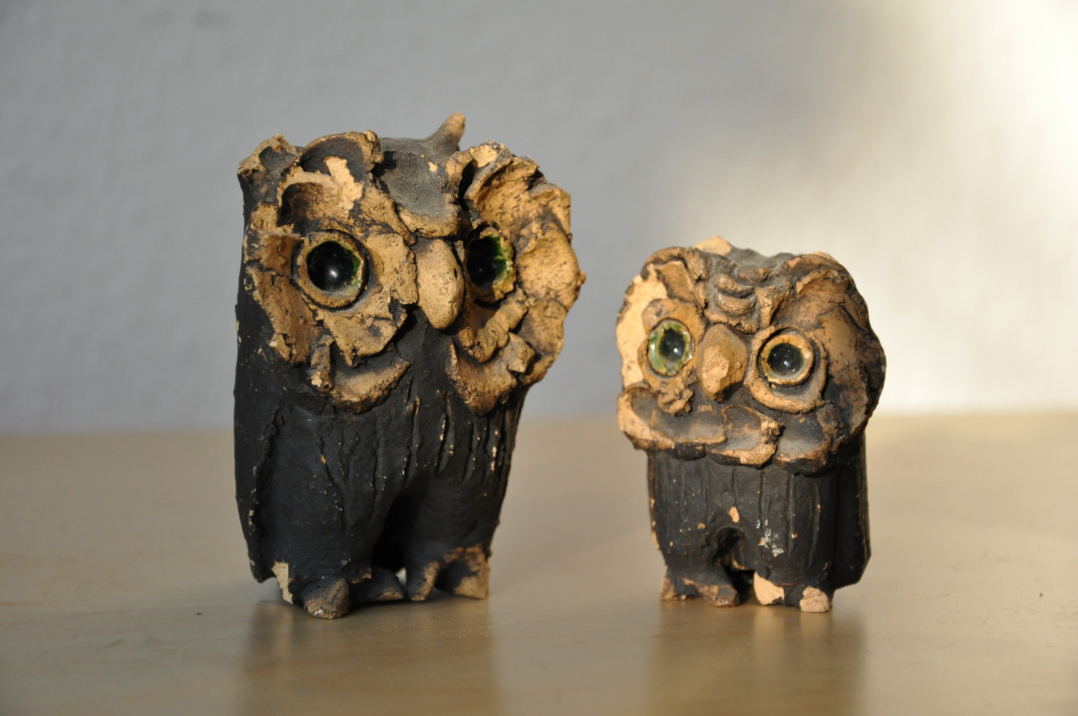 two small carved owls with green eyes, standing next to each other