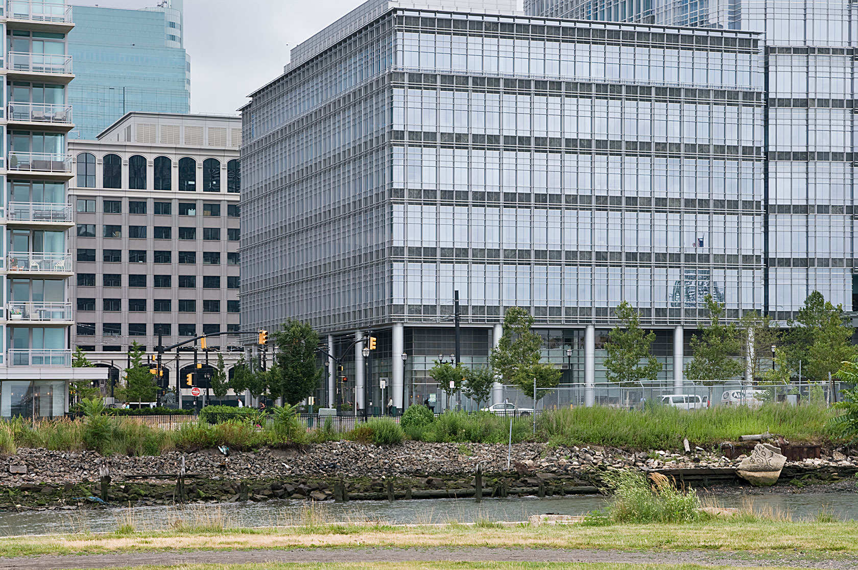 some buildings are on the shore with grass and bushes