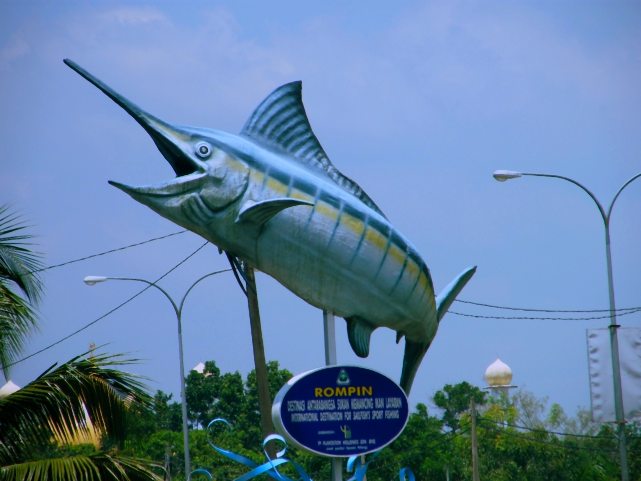 two big fish hanging from telephone poles next to a blue sign