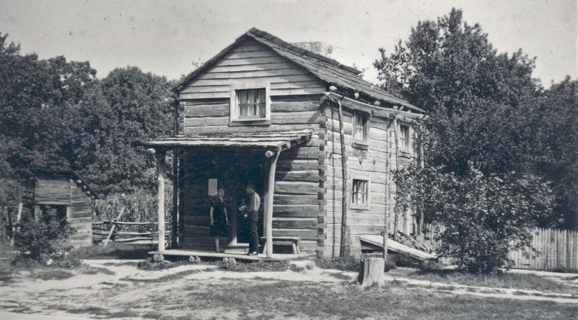 a black and white po of a man opening an outhouse