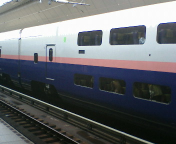 a long blue and white train is parked next to a platform