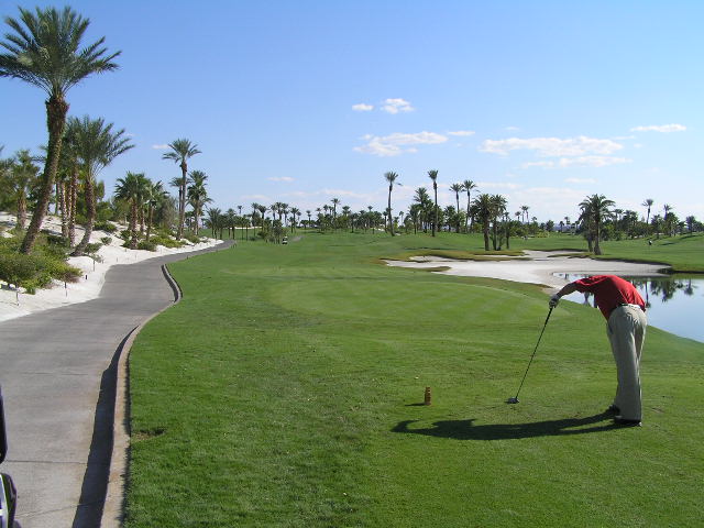 a man teeing off at a golf course next to a lake