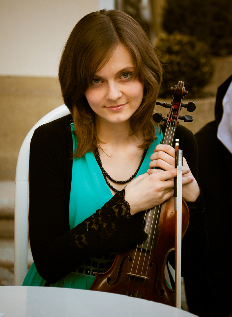 woman sitting in chair holding up violin