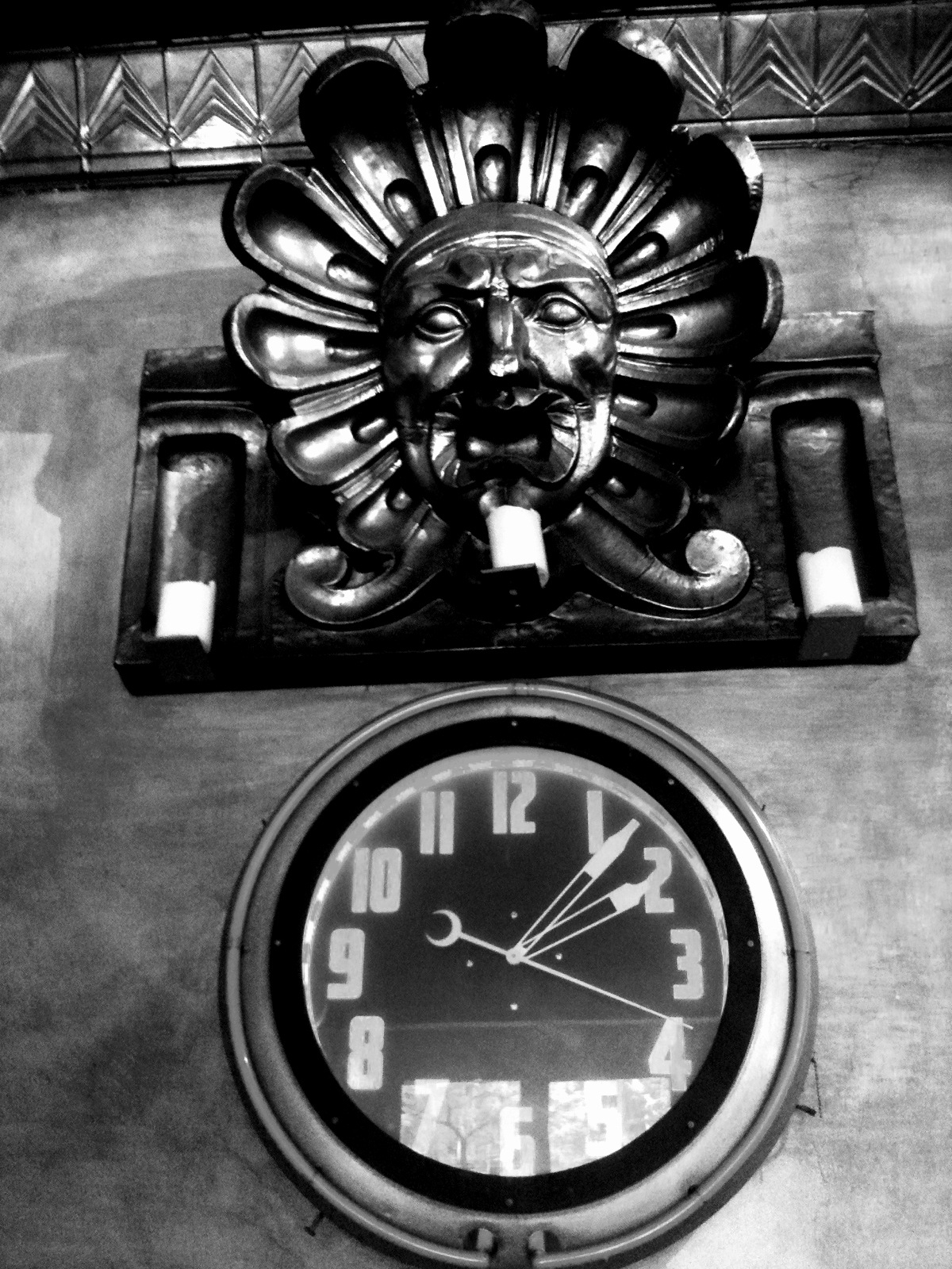 a clock showing nine o'clock with lion's head on the wall