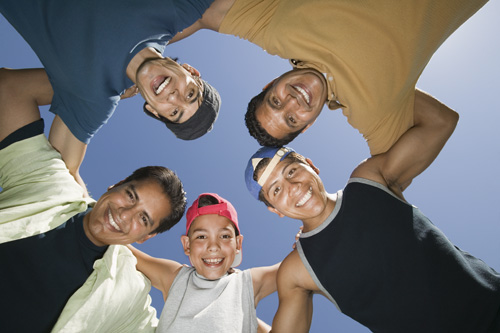 four people standing in a circle smiling and looking up at the camera