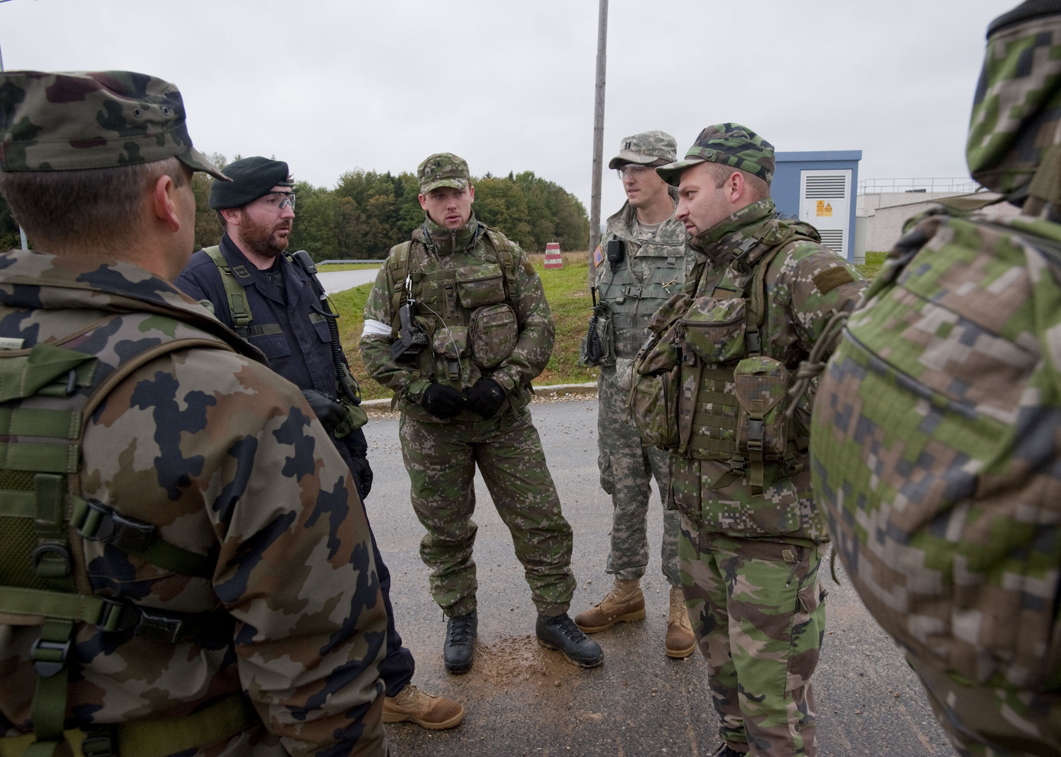 military men in uniforms talking while standing on the side of the road