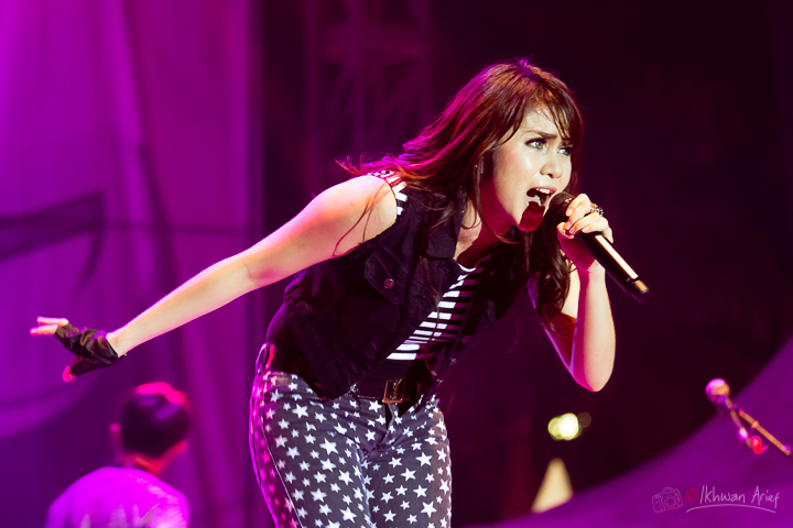 a woman with black and white top and black skirt holding a microphone